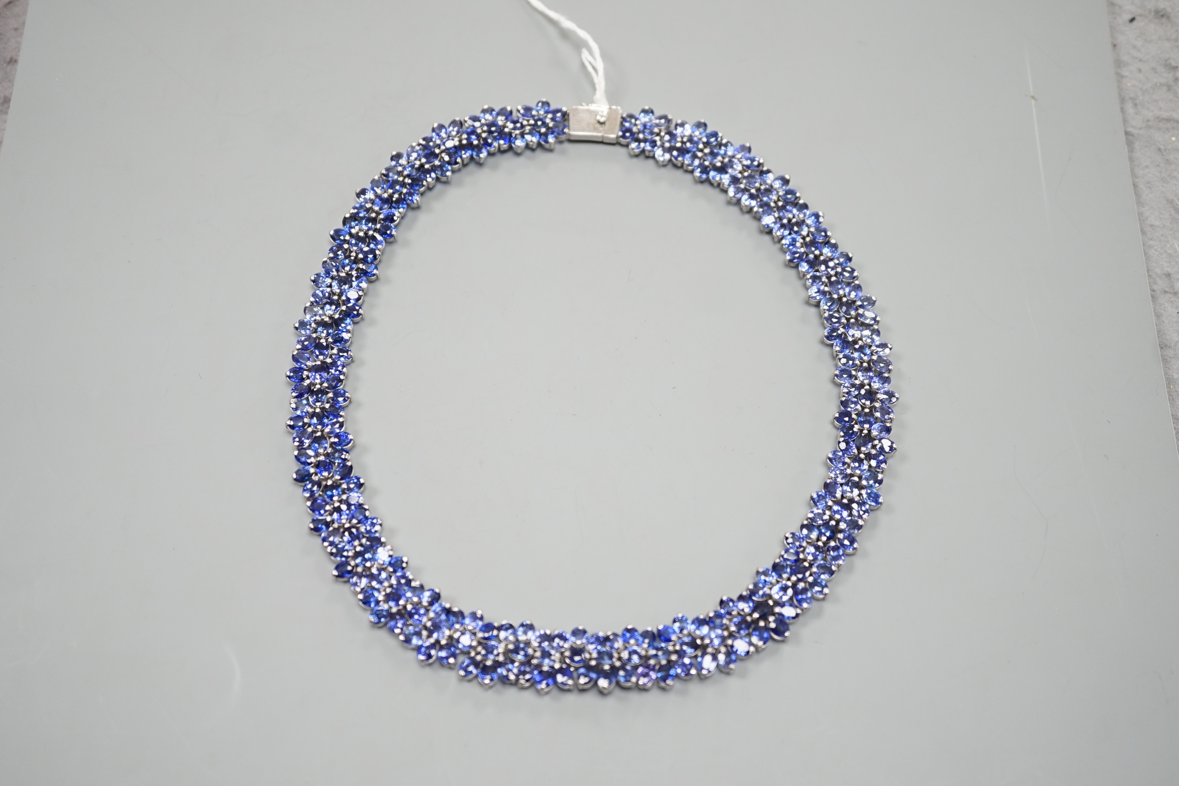 A continental base metal and synthetic sapphire? flower head cluster set necklace, approximately 39cm.